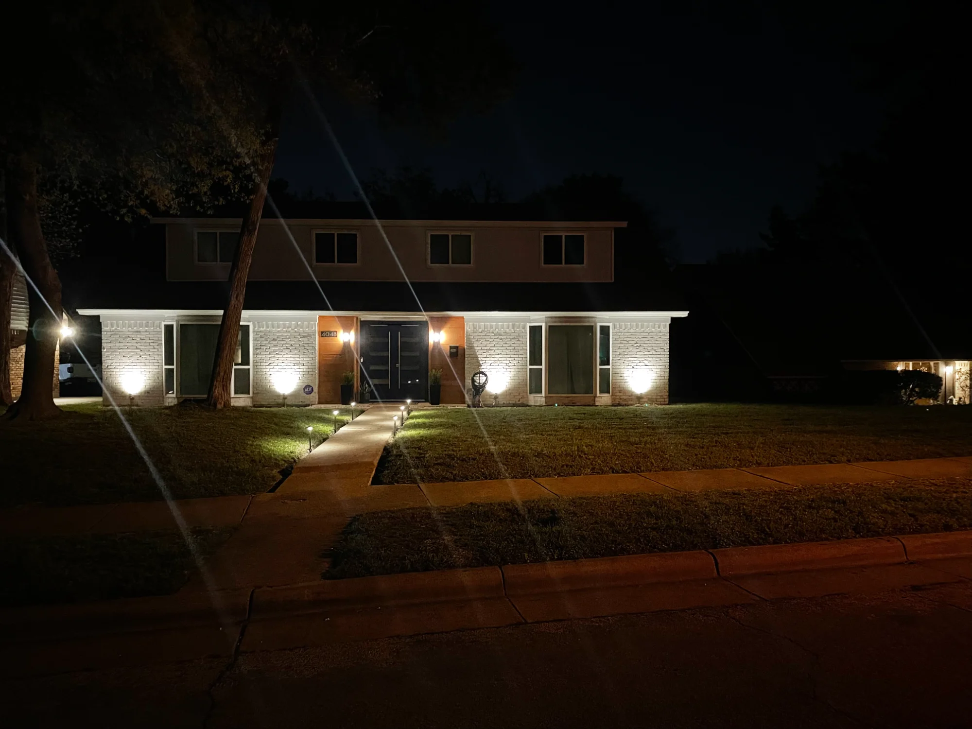 Landscape uplighting accenting mature trees after dark